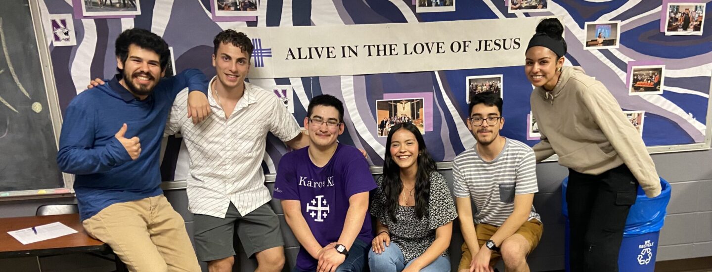 The CaSA Board for the 2023-2024 academic year. The students are standing against a colorful wall that says "Alive in the love of Jesus." There are six diverse students smiling and looking into the camera.